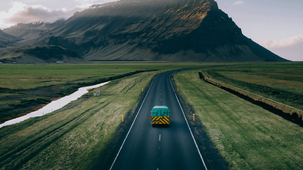 Cyan Branded IMSERV Van on road with a mountain background